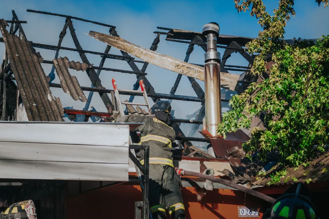 Firefighter working over a fire-damaged roof structure