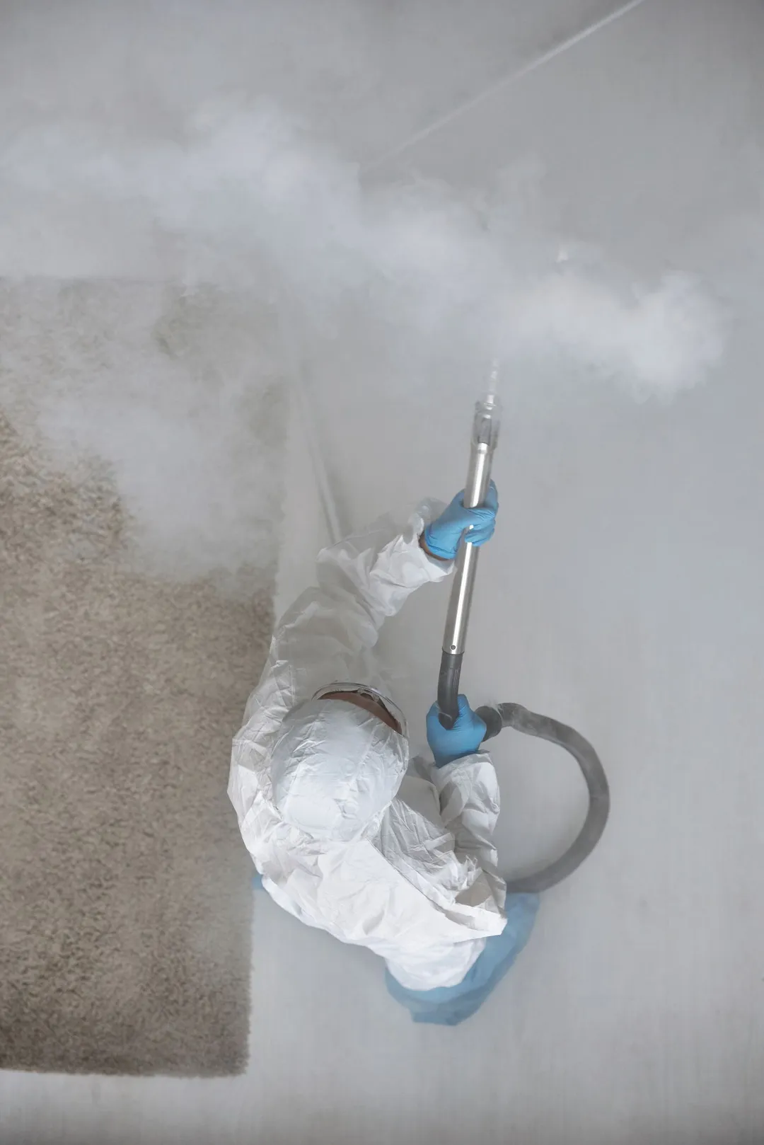 Technician in protective gear fog-treating a room